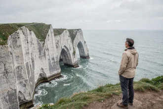 Touriste admirant les falaises d'Étretat et l'arche naturelle de la Porte d'Aval sur la côte d'Albâtre en Normandie